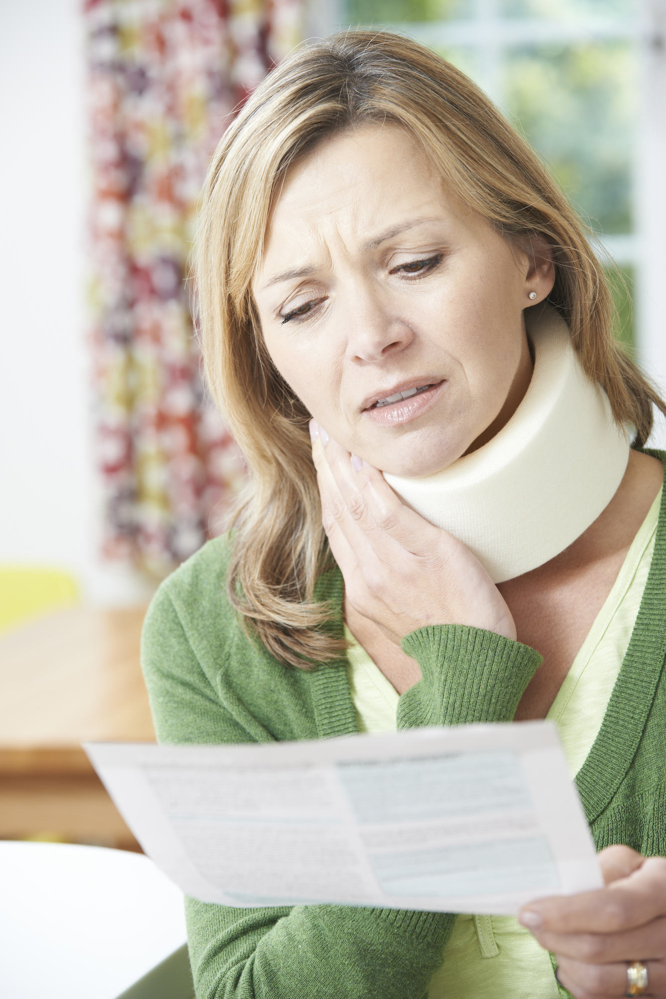 workers compensation lawyer-woman reading paper while wearing neck brace